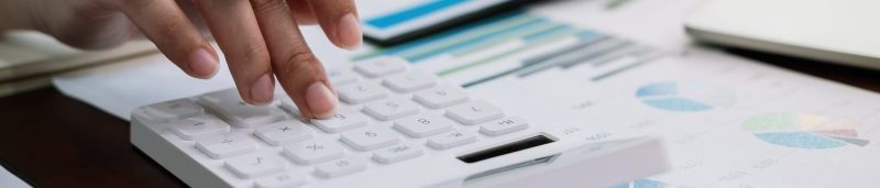 Close up accountant or bookkeeper banker making calculations with calculator. Savings, finances and economy concept.